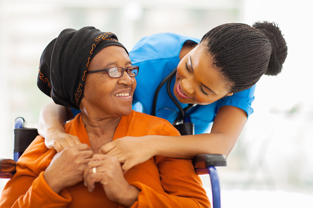 A caregiver hugging a smiling senior woman