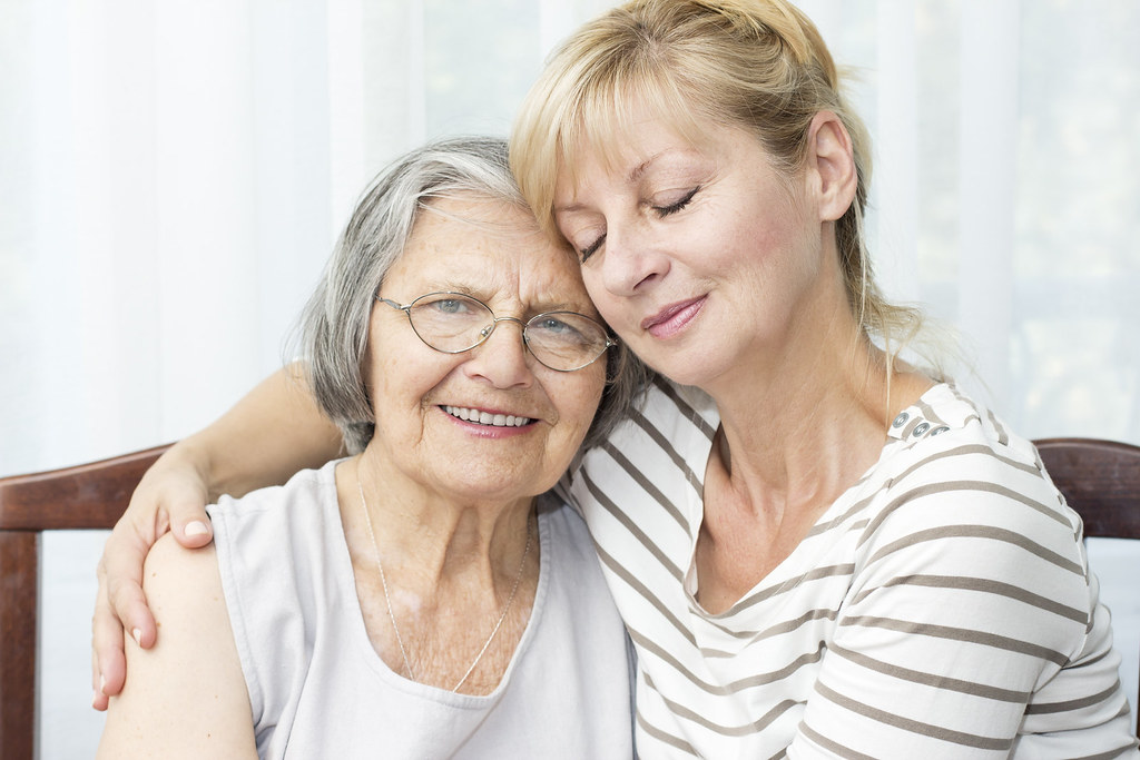 An elderly woman smiling with a younger companion